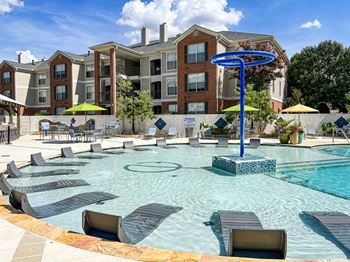 A large swimming pool surrounded by lounge chairs and umbrellas at Quail Ridge Apartment Homes, Bartlett